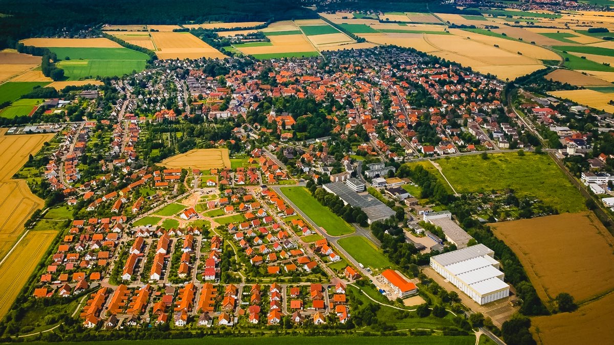 Luftbild des Ortskerns von Wennigsen: rote Ziegeldächer, umgeben von Feldern, am Horizont der Deisterwald